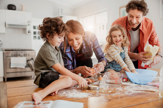 Young caucasian family being messy and having fun baking together in the kitchen