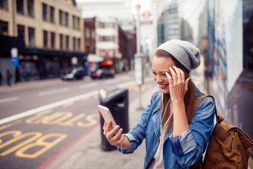 Young woman using a smart phone while walking down a sidewalk in London
