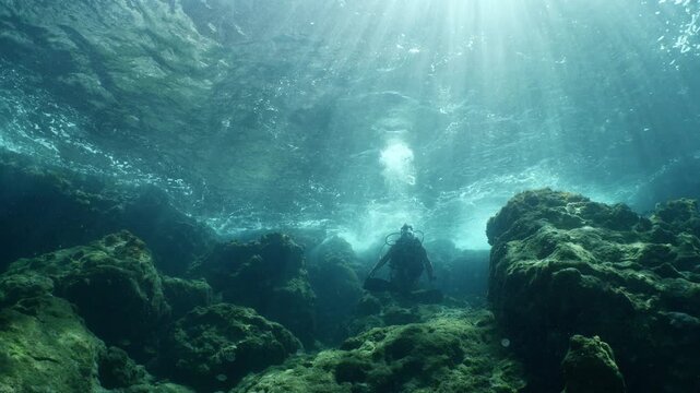 scuba diver howers like budha underwater with waves under sun beams and rays yogo meditation