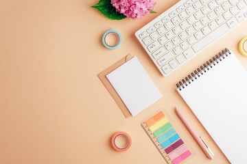 Home office desktop with computer keyboard, notepad, envelope with blank card, pen and color...
