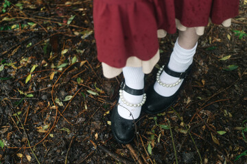women's feet in black shoes and white socks in a park on the grass