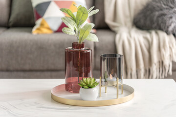 Contemporary coffee table decor with burgundy glass vase holding green foliage, black candle holder...