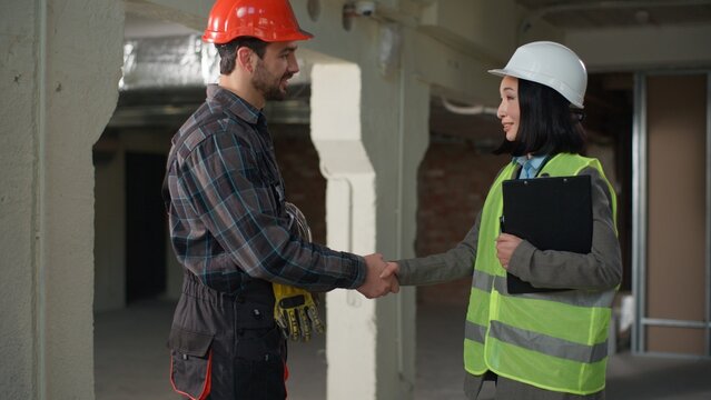 Business multiethnic diverse builders handshake partnership agreement building construction project cooperation Asian woman inspector hardhat shaking hands Caucasian man engineers teamwork architects
