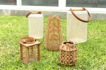 Assorted decorative lanterns and woven baskets with natural fibers and leather handles arranged on...