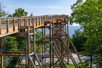 A man walking on a boardwalk high above the trees and Lake Michigan in Peninsula State Park in Wisconsin. 
