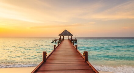 Fototapeta premium A wooden pier extends into the calm ocean at sunset