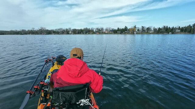 Kayak angler finesse fishing in the lake, using kayak, spinning rod and small lure. Fisherman kayaking in the North American waters, fishing and trolling fishing. Water sport in spring. Fishing game.