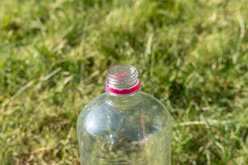 A bottle with a pink cap is sitting on a grassy field