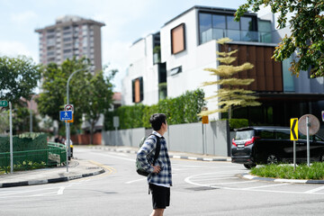 Man standing at a street pedestrians in a residential area with modern houses and a high-rise building