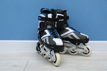 Pair of roller skates on floor near light blue wall