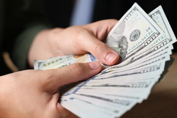Woman counting money at table indoors, closeup
