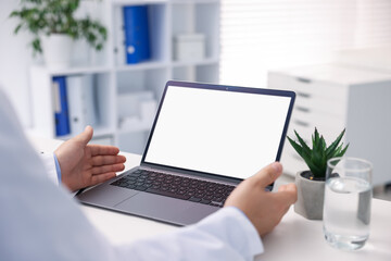 Doctor having online consultation via laptop in clinic, closeup
