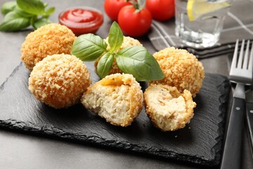 Delicious fried croquette balls with basil on grey table, closeup