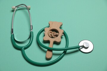 Pediatrics concept. Stethoscope and toy on turquoise background, closeup