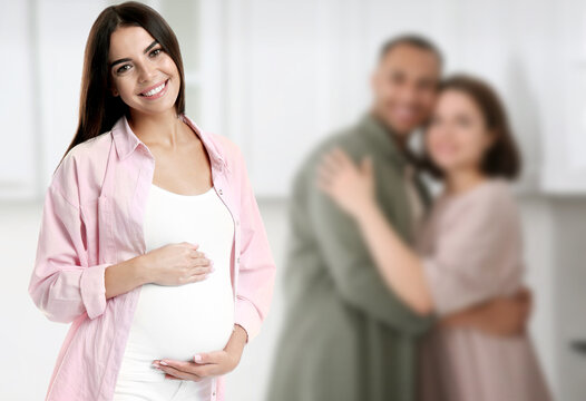 Surrogate mother and intended parents indoors, selective focus