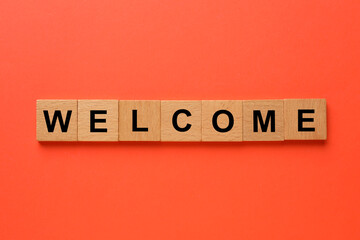 Word Welcome made of wooden cubes on red background, top view