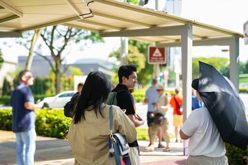 A group of people are waiting at a covered bus stop in an urban setting