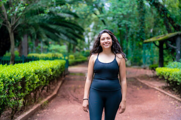 Sporty Latina woman walking along a tree-lined path in Parque México, enjoying a healthy lifestyle...