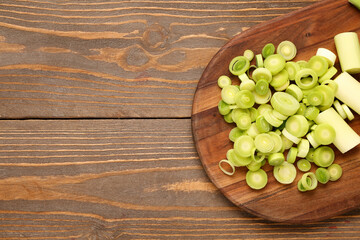 Board with slices of fresh leek on wooden background