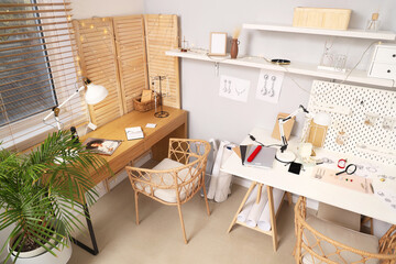 Sketches of stylish accessories with tools on jeweler table in workshop