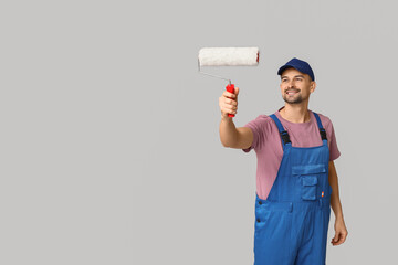 Portrait of male painter with paint roller on grey background