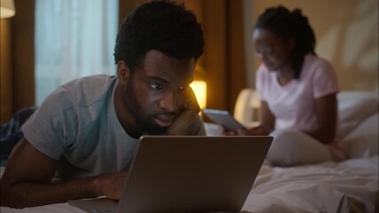 African American couple husband lying bed work laptop wife using digital tablet at home bedroom night family evening relaxation relationship problems gadget addiction spouses browsing internet indoor - Powered by Adobe