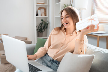 Young woman with gift card and laptop shopping online at home