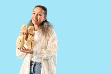 Female shoemaker with wooden shoe trees on blue background