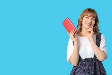 Beautiful young woman holding red wallet on blue background