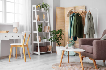 Interior of dressing room with clothes rack, armchair and tables