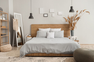 Interior of beautiful modern bedroom with pampas grass and mirror