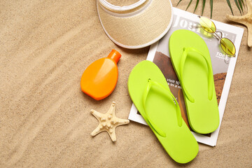 Composition with stylish female flip-flops, beach accessories and magazine on sand