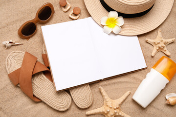 Composition with blank open book, stylish beach accessories and sunscreen on sand