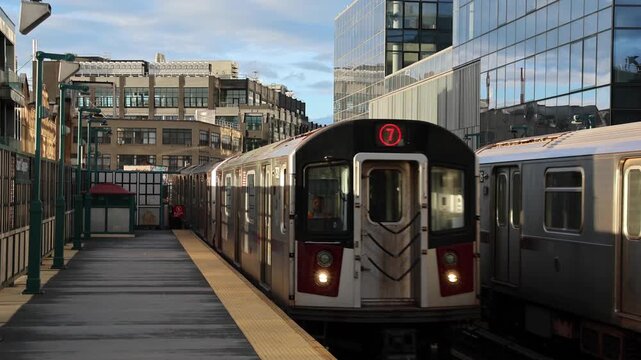 train arriving on platform in court square queens long island city new york nyc famous outdoor elevated station stop seven 7 metro commuter line tall buildings in background tracks railroad track