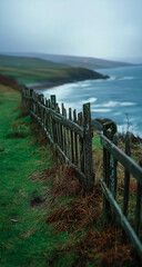 Fototapeta premium A lovely rugged coastal path is framed by a weathered wooden fence, which takes on a natural, timeless look using soft-toned film.