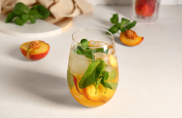 Glass of fresh peach lemonade with mint on white background, closeup