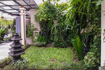 serene outdoor garden showcasing lush green foliage, a traditional stone pagoda, and decorative statues, creating a tranquil oasis.