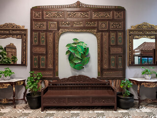 Rich Javanese interior with ornate wooden carvings, a traditional bench, and decorative mirrors, evoking classic Indonesian elegance.