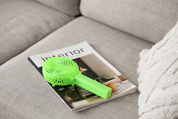 Small electric fan and magazine on sofa