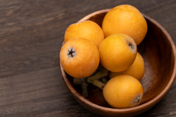 harvested loquats are placed in a wooden bowl on the table, Japan.