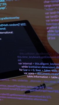 Tablet with programming code and pen on wooden desk, animation showing