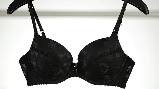Elegant Black Bra Hanging on a Hanger Against a White Background