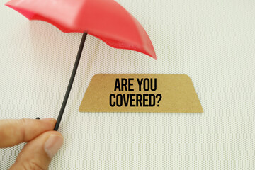 hand holding an umbrella with the question Are You Covered insurance coverage concept 