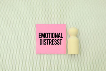 wooden figure and pink paper with the word emotional distress. mental suffering as an emotional...