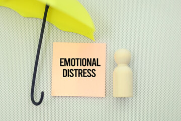 wooden figure and pink paper with the word emotional distress. mental suffering as an emotional...