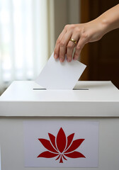 Hand placing ballot paper in white ballot box