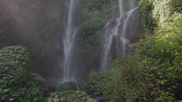 Slow motion footage of Sekumpul Waterfalls in Bali, Indonesia. Multiple tall streams cascade through a lush green jungle, creating a dramatic and tranquil tropical nature scene.