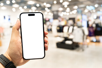 Hand Holding Blank Smartphone in Blurred Retail Environment. for illustrating concepts such as mobile advertising in store digital engagement. displaying any custom content on the screen.