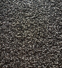 A close-up of an interior wall features a textured finish made of small, dark and light stone...