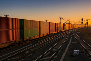 Fototapeta premium Cargo Train at Sunset: Colorful Containers on Tracks Under Golden Sky